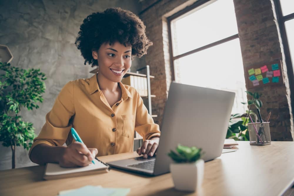 A young African American woman sitting at a desk with a laptop, utilizing Horizon Outdoors as her training platform.