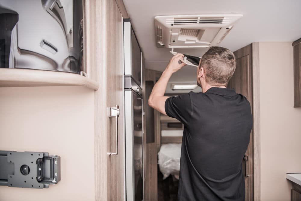 A man, Tracy Anglemeyer, Director of Recruitment at RV Technical Institute, installing a vent fan in an RV.