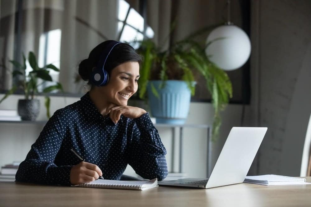 A woman wearing headphones is sitting at a desk with a laptop during an RVDA Convention/Expo.