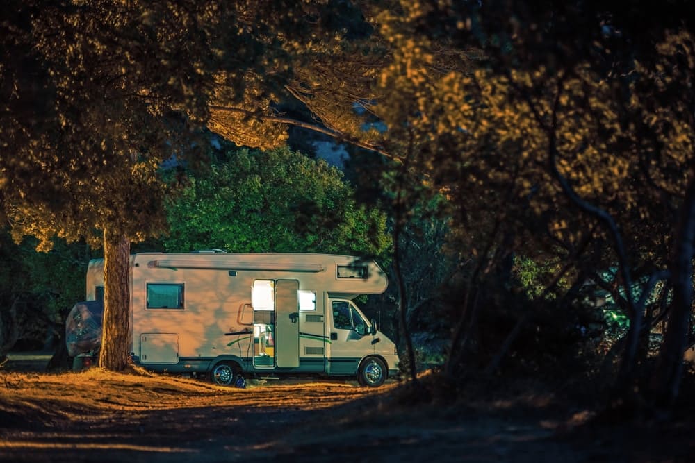 A Senate-approved outdoor recreation package features an RV parked in the serene woods at night.