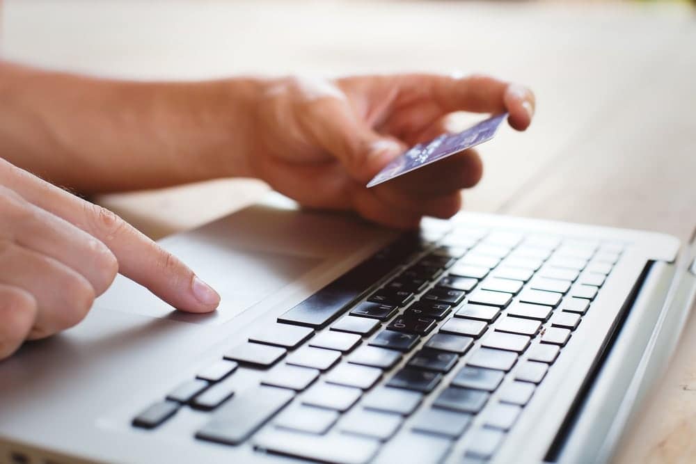 A person holding a credit card and making a purchase on a laptop.