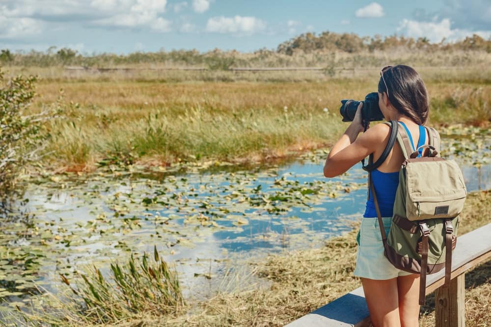 A woman is capturing the beautiful marshland scenery, promoting wildlife conservation and encouraging recreation opportunities.