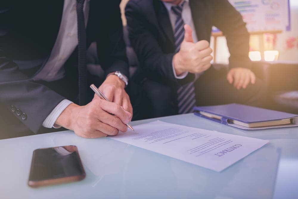Two businessmen signing a contract to Buy.