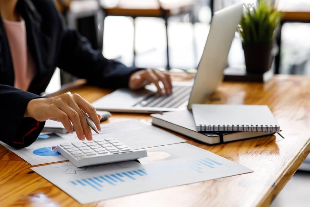 A business woman, employed at Winnebago Industries, utilizing a calculator on a wooden table during the First Quarter Fiscal 2022.