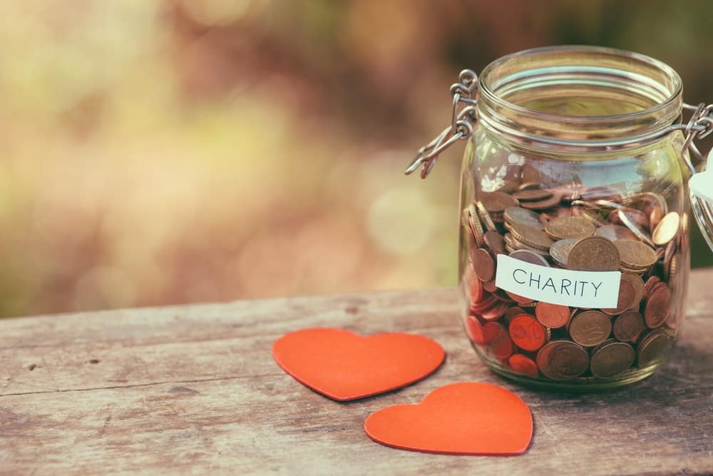 A jar with coins and hearts on a wooden table.