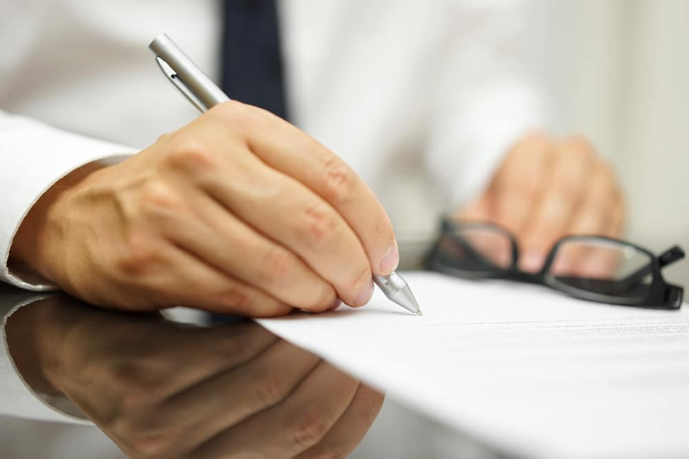 A man acquires THOR Industries by signing a document with glasses.