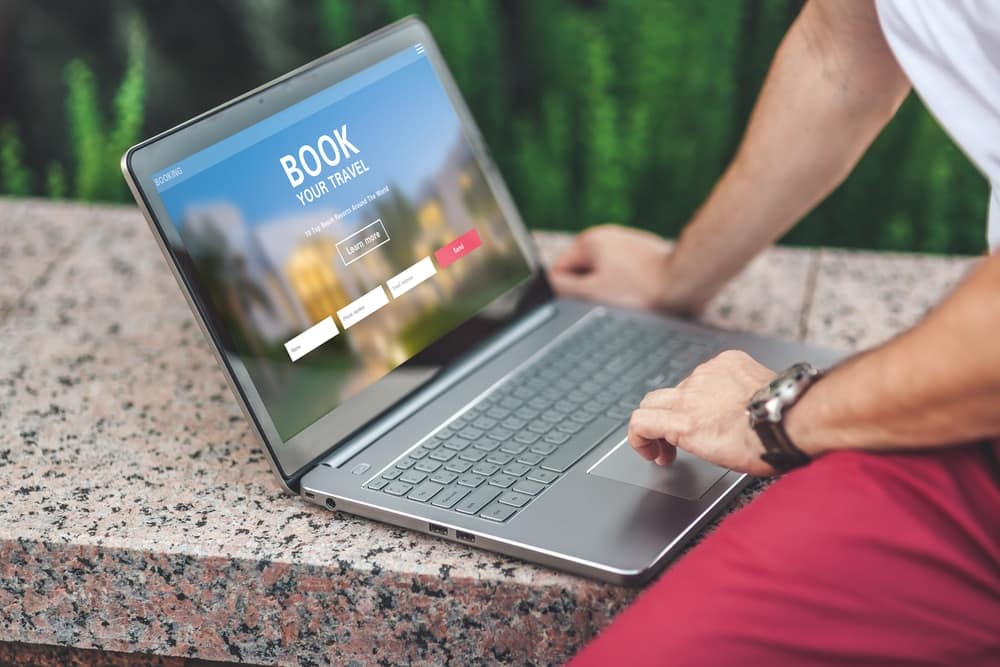 A man is using a laptop with the word book on it.