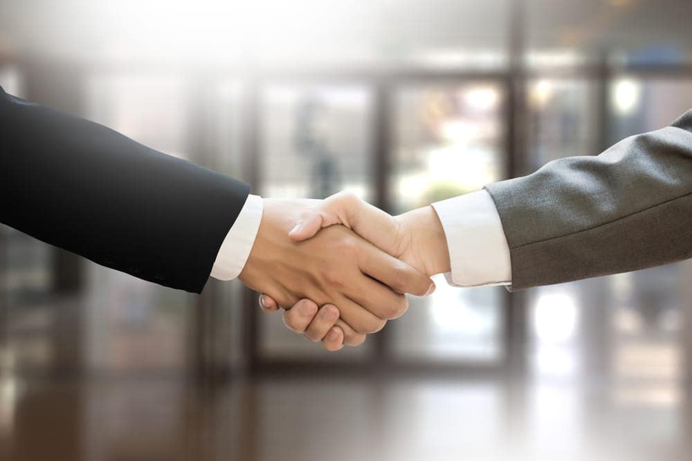 Two businessmen from Monomoy acquire the building and sign an agreement while shaking hands.