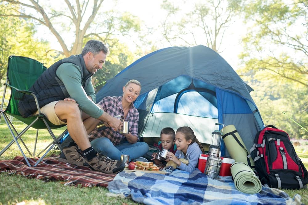 A family is having a picnic near their tent at a holiday camp.
