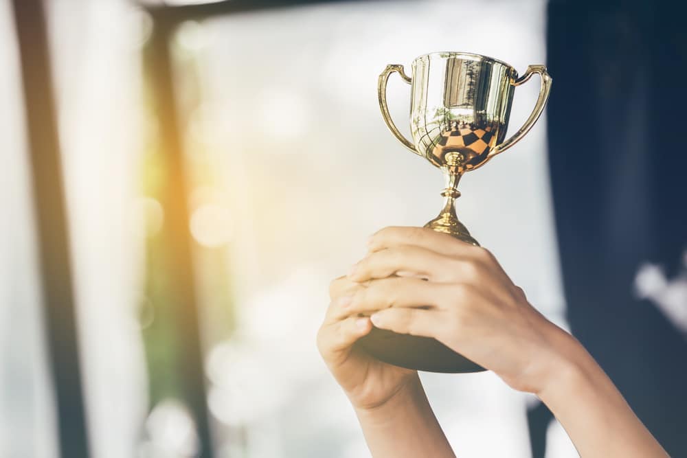 A woman holding up a trophy in front of a window.