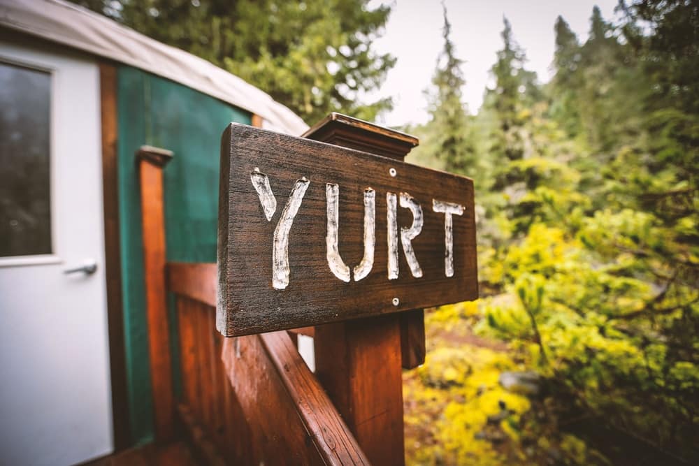 A **secluded** wooden sign with the word yurt on it.