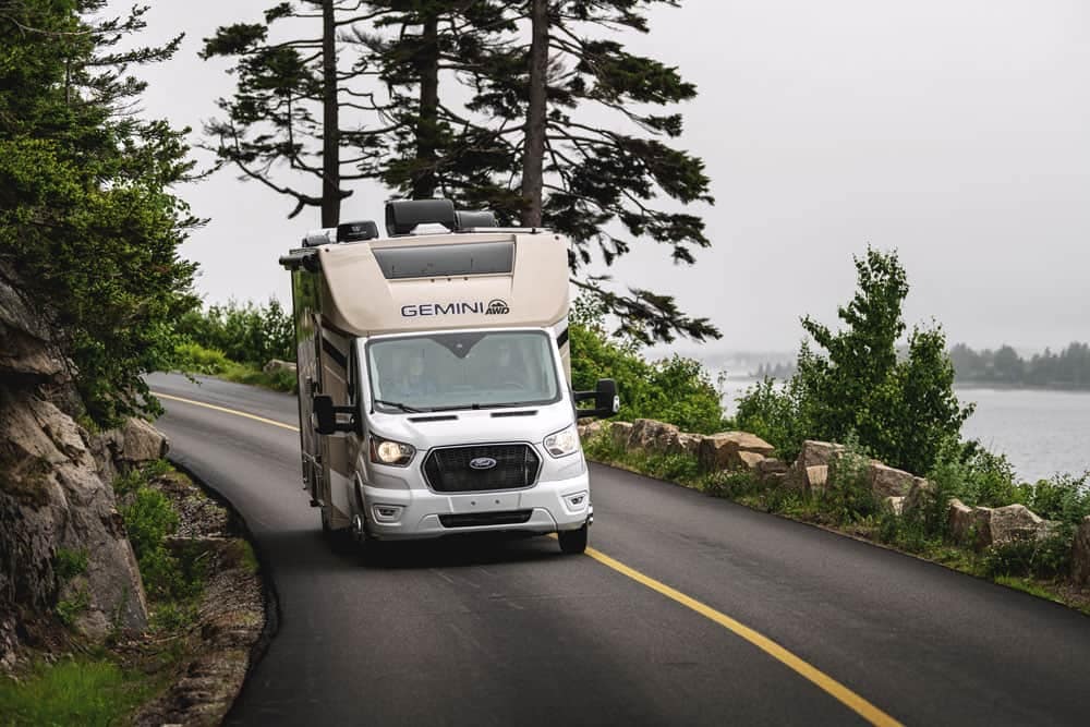 A Thor Motor Coach rv driving down a winding road near a lake at the Florida RV SuperShow.