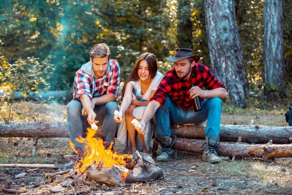 Three friends sitting around a campfire in Manitoba parks.