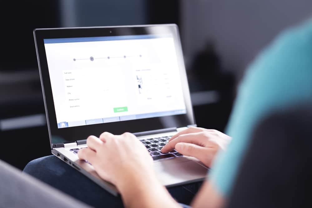 A person is using a laptop on a couch.