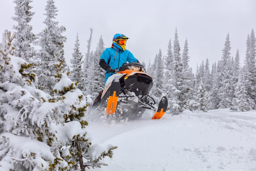 A person riding a snowmobile on a snowy trail in Michigan, indulging in exhilarating winter outdoor recreation.
