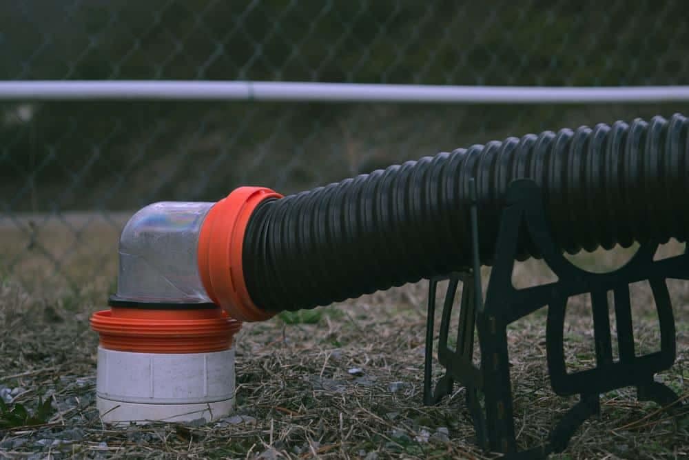 A black hose next to a fence.