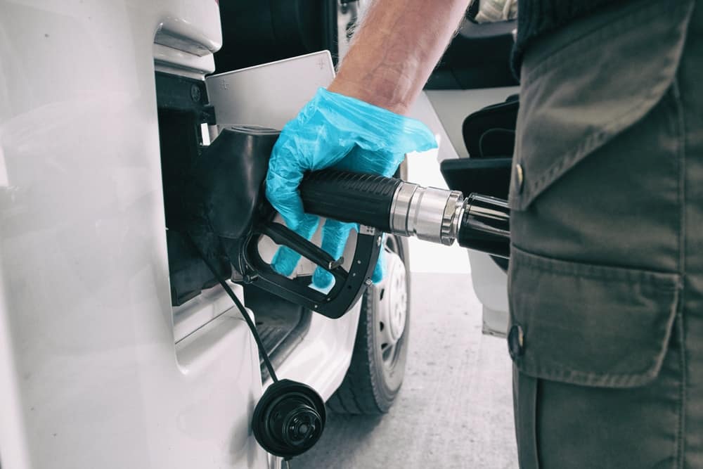 A man is filling up a gas tank at a gas station.