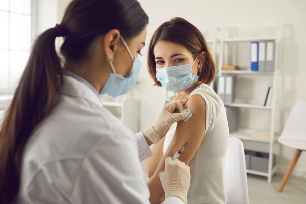 A woman is receiving an employer-required vaccine from a doctor at Indiana House.