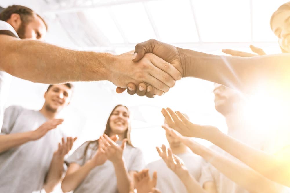 A group of people shaking hands in front of a group of people.