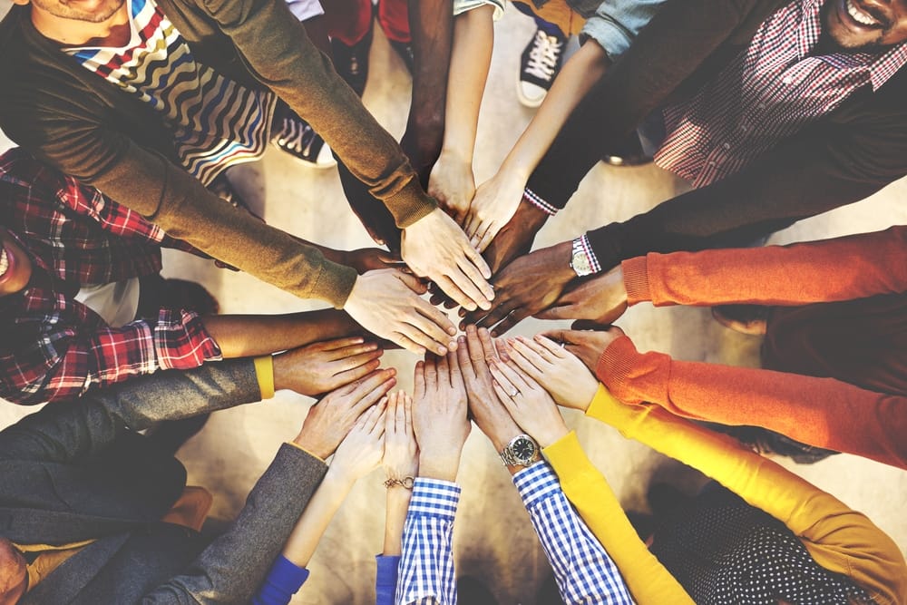 A team of people putting their hands together in a circle.