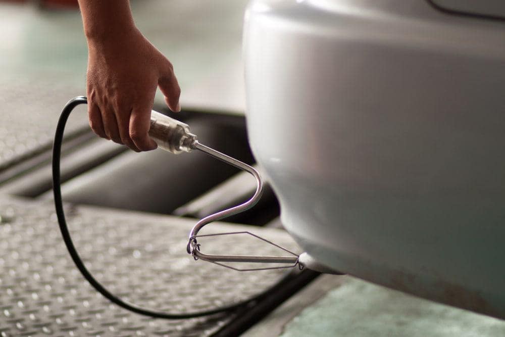 In California, a person is using a hose to clean a car while complying with vehicle emissions standards.