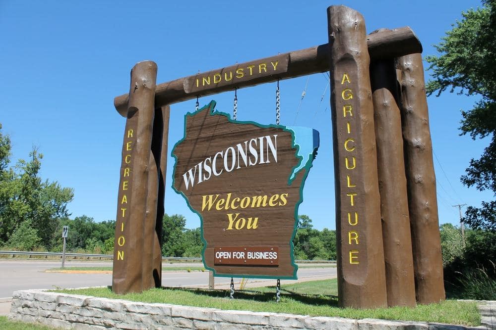 Wisconsin tourism welcome sign showcasing the state's natural beauty with a backdrop of a wooded area.