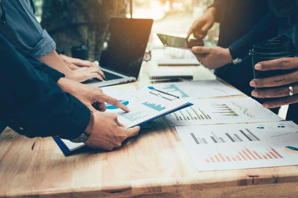 A group of Sales Leadership business people looking at Octane graphs on a table, which strengthens their strategies and decision-making.