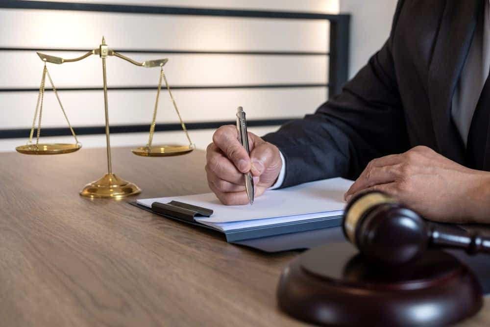 A man in a suit writing on a piece of paper.