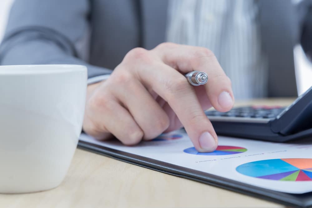 A businessman holding a calculator and a cup of coffee during a conference call.