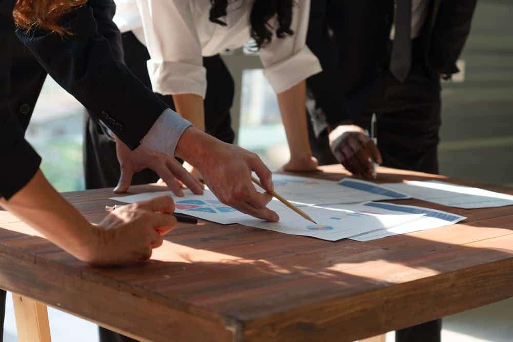A group of business people pointing at a piece of paper, discussing a potential expansion plan for the Wild Animal Park.
