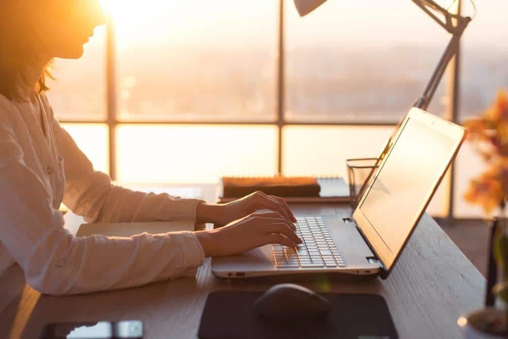 A woman working on her laptop in front of a window, envisioning the future of Pitchup.com with her team.