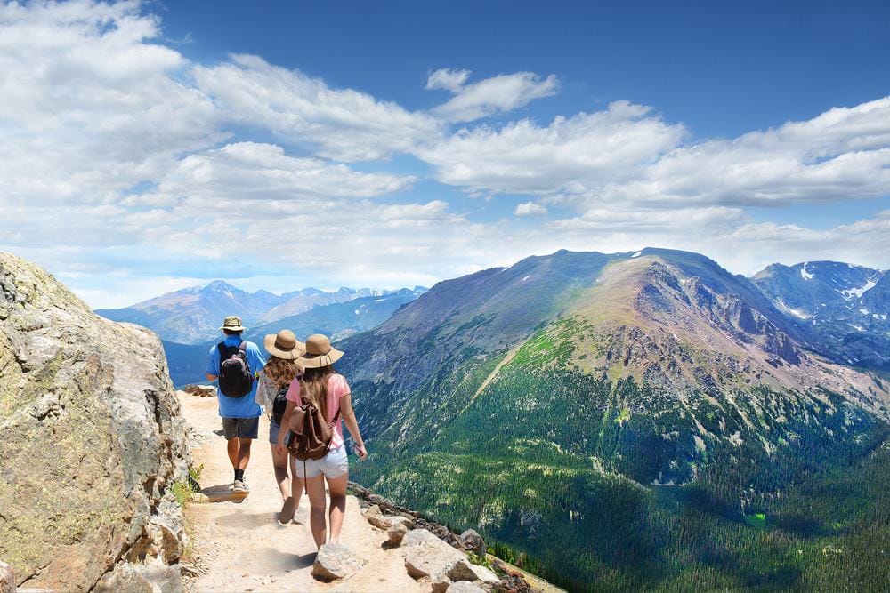 A group of people engaging in outdoor recreation hiking on a trail in the mountains, contributing to economic growth and benefiting rural areas.
