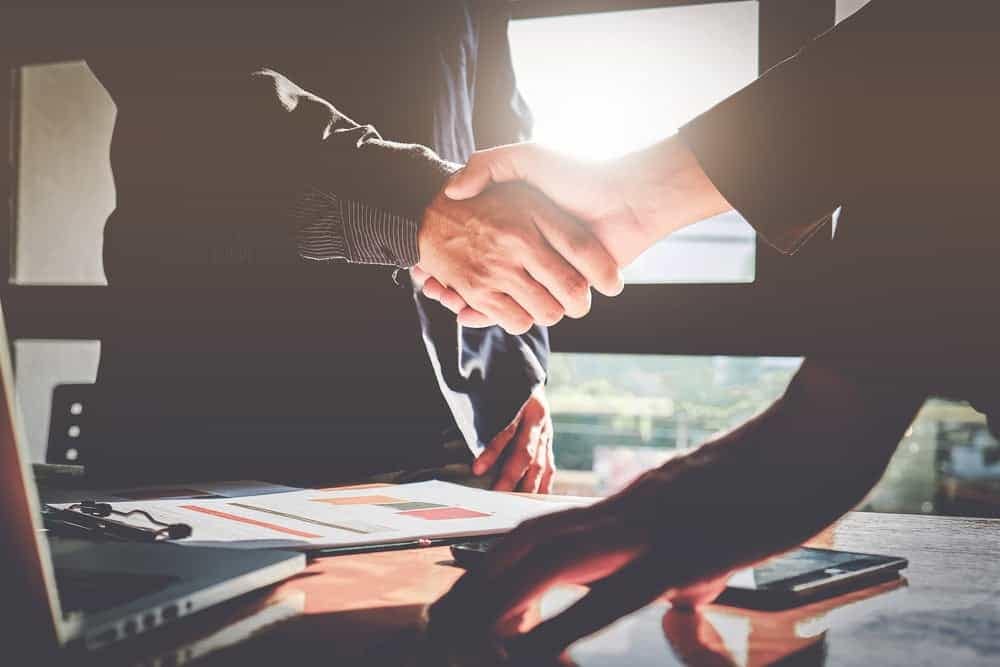 Two business people from Forrest Street Partners shaking hands in front of a desk, as the company expands its portfolio by investing in an MH community.