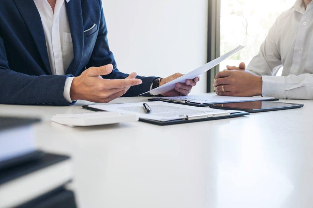 Two businessmen from the Hilb Group discussing insurance resources at a table.