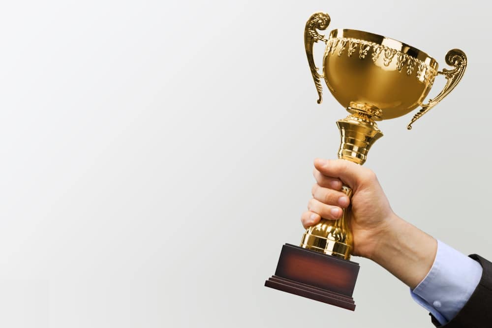 A man holding up a gold trophy in British Columbia, showcasing the excellence of tourism and hospitality in the region.