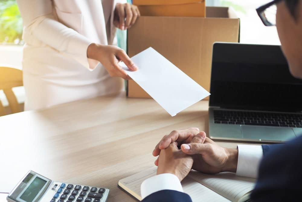 A businessman handing over a letter to a woman at a desk in the context of BC Trail Development or the Outdoor Recreation Council.