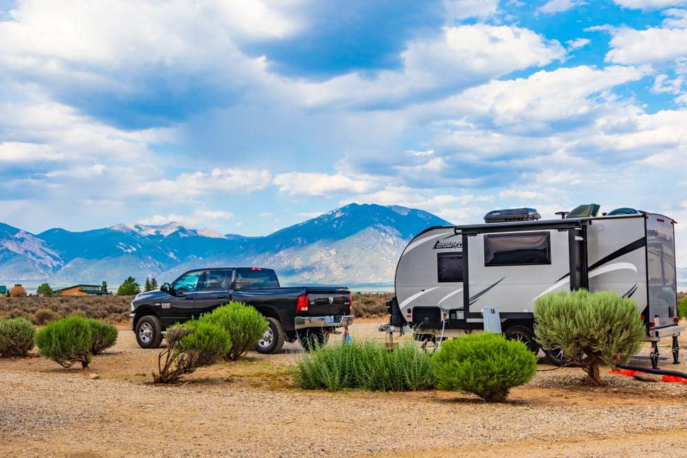 An accessible RV parked in a dirt lot with mountains in the background.