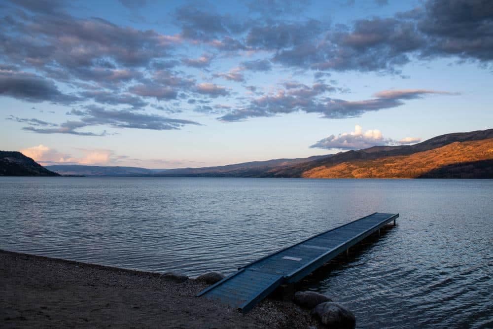 A waterfront dock on Okanagan Lake with mountains in the background.