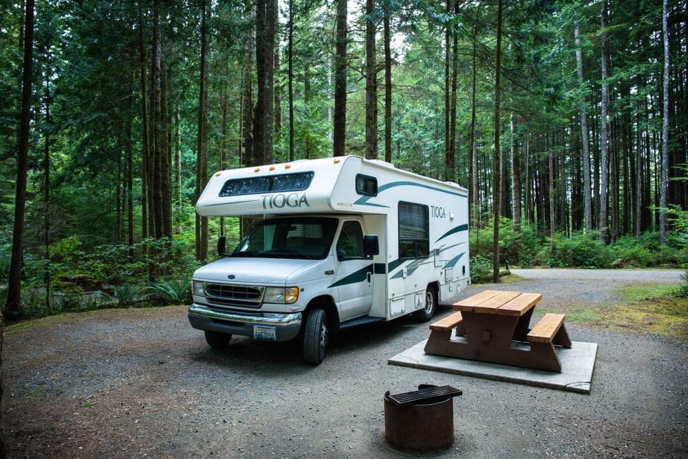 A white rv parked in a wooded area.