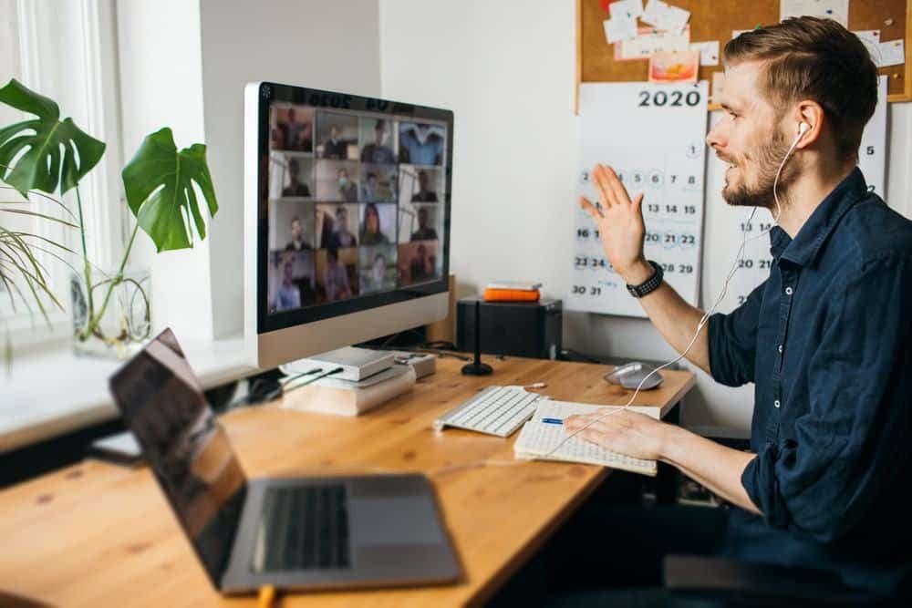 A man is participating in an informative session at the Canadian Outdoor Hospitality Conference & Expo, sitting at a desk with a laptop and a video camera.