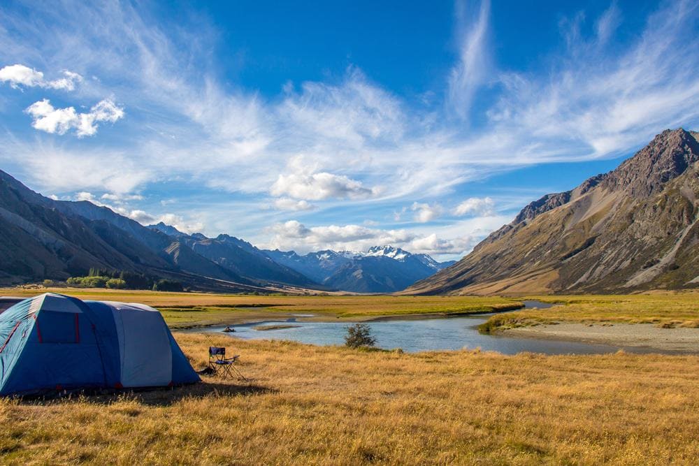 A campsite set up in a field next to a river.