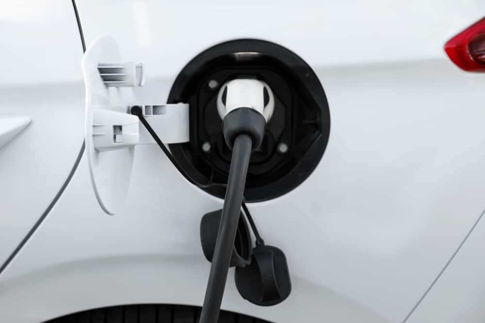 A white car is plugged into an EV charging station.