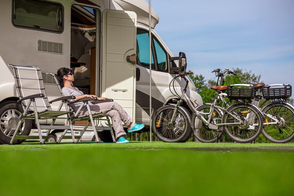 A woman sits in front of an RV parked at the Eckville RV Park.