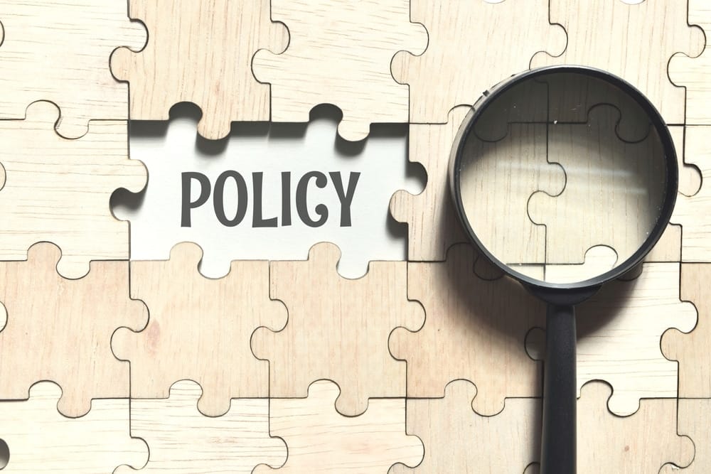 A magnifying glass over a puzzle piece with the word policy, showcasing the importance of policy priorities in the RV industry.