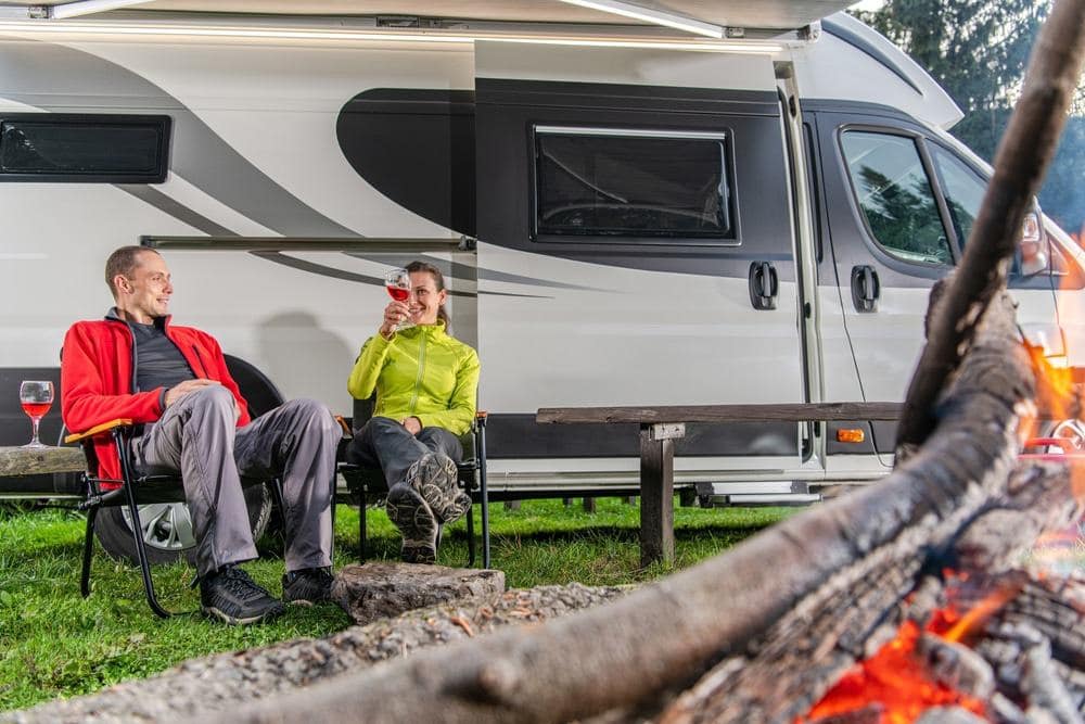 Two people sitting around a campfire in front of an RV in Alabama.