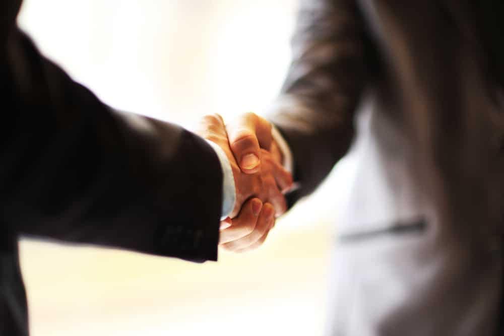 Two businessmen, Carl Esposito and another member of the Board of Directors from Shyft Group, shaking hands in a business meeting.