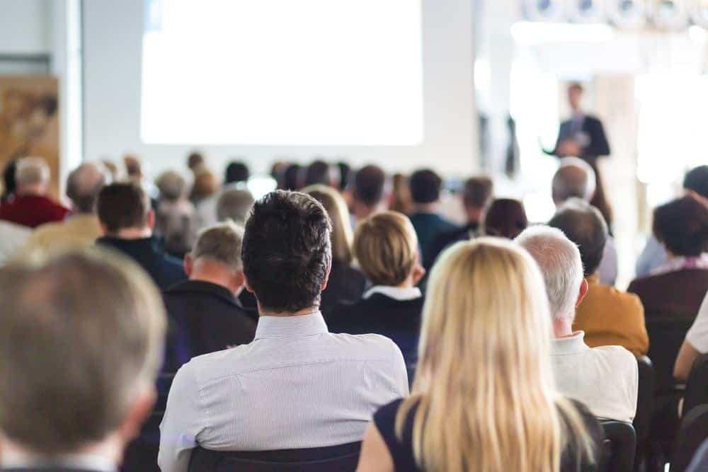 A group of people in a conference room watching a Louisiana-inspired presentation.