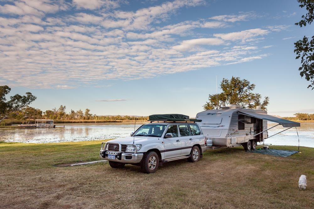 A caravan parked on a grassy area near a lake, attracting weekend surge of tourism operators and caravan park owners.