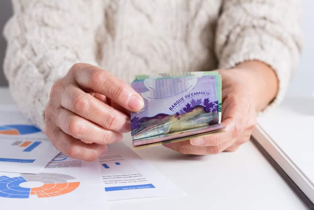 A woman holding a swiss franc in her hand outside the Robert Service Campground Building.