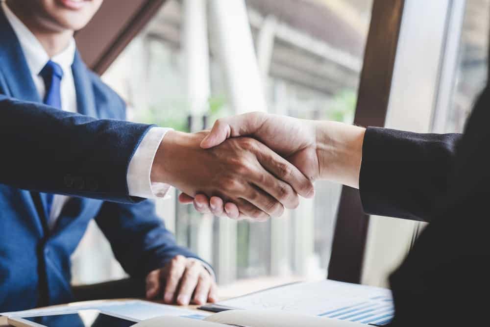 Two businessmen shaking hands in front of a desk at an Idaho Visitor Center.